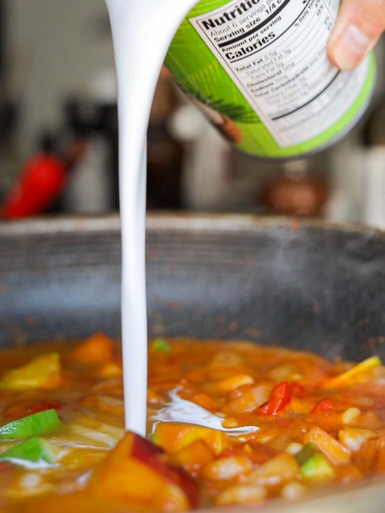 adding coconut milk to curry sauce